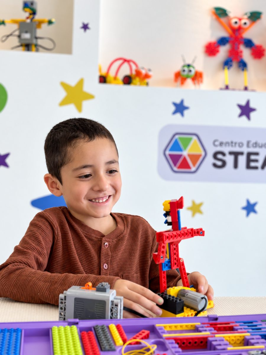 Niño sonriente construye un robot de bloques en Centro Educativo STEAM